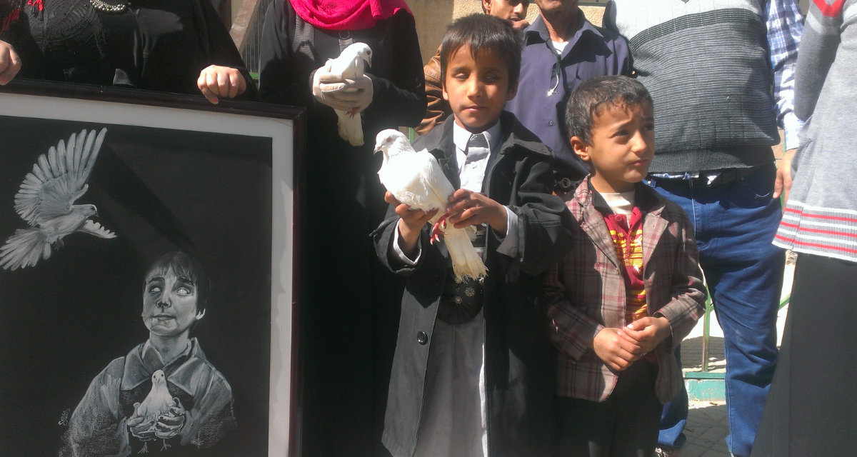 Ein blindes Kind trägt eine Taube bei einem Protest gegen den Angriff auf das al-Nour Center for the Blind in Sanaa, Jemen 2016 | Wikipedia | VOA/Almigdad Mojalli | gemeinfrei Ein blindes Kind trägt eine Taube bei einem Protest gegen den Angriff auf das al-Nour Center for the Blind in Sanaa, Jemen 2016 | Wikipedia | VOA/Almigdad Mojalli | gemeinfrei
